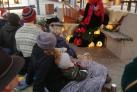 Kvinde på torvet med nissehue fortæller julehistorier foran siddende børn og forældre